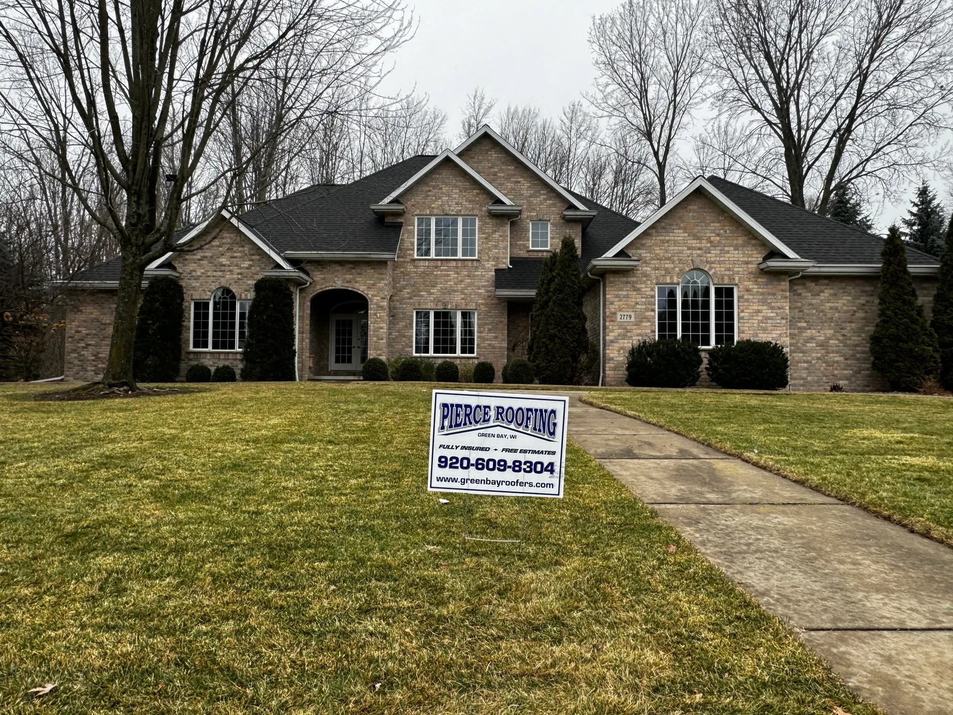 Brick two-story home in Howard WI after hail damage roof replacement by Pierce Roofing